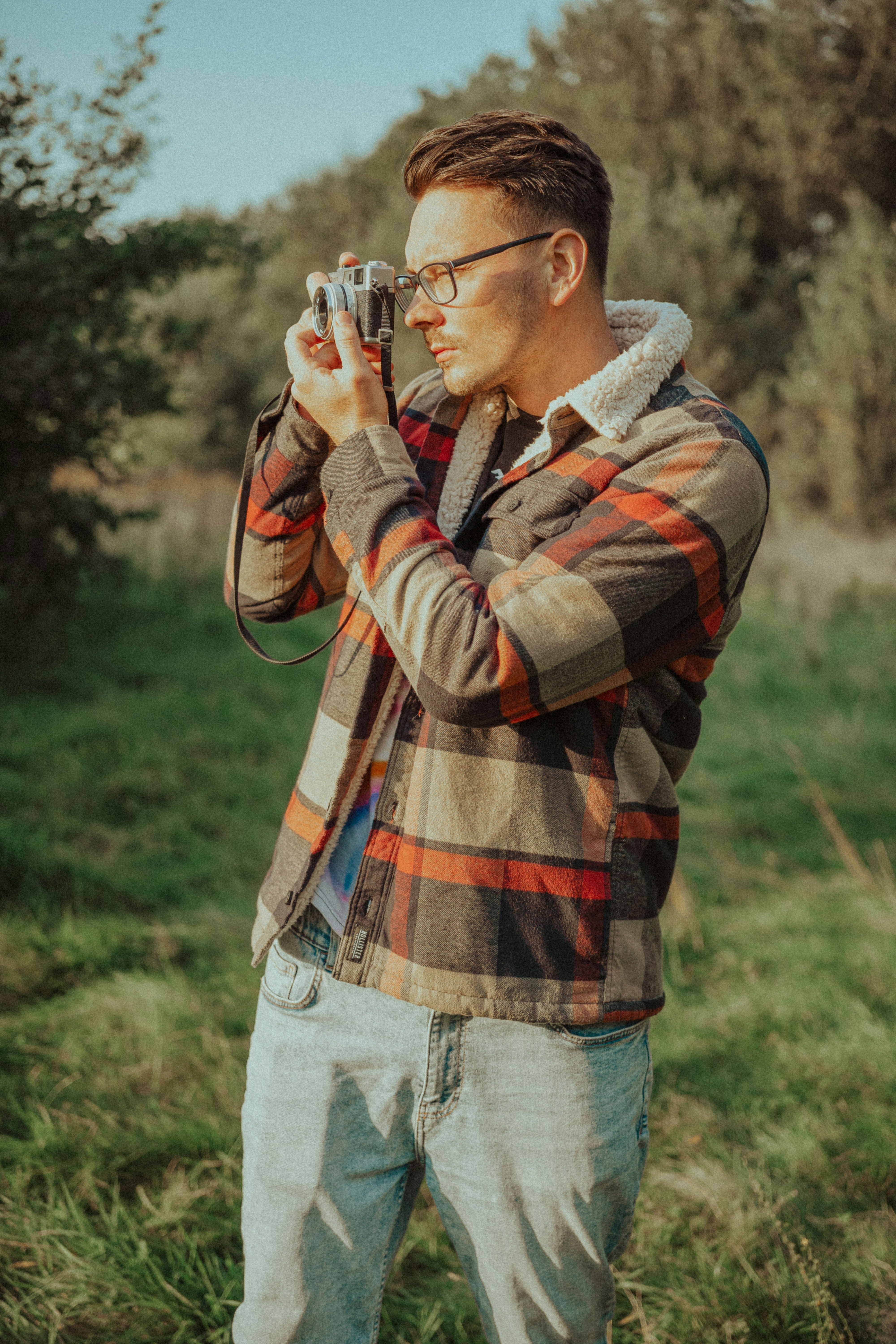 man in brown and black plaid dress shirt holding camera